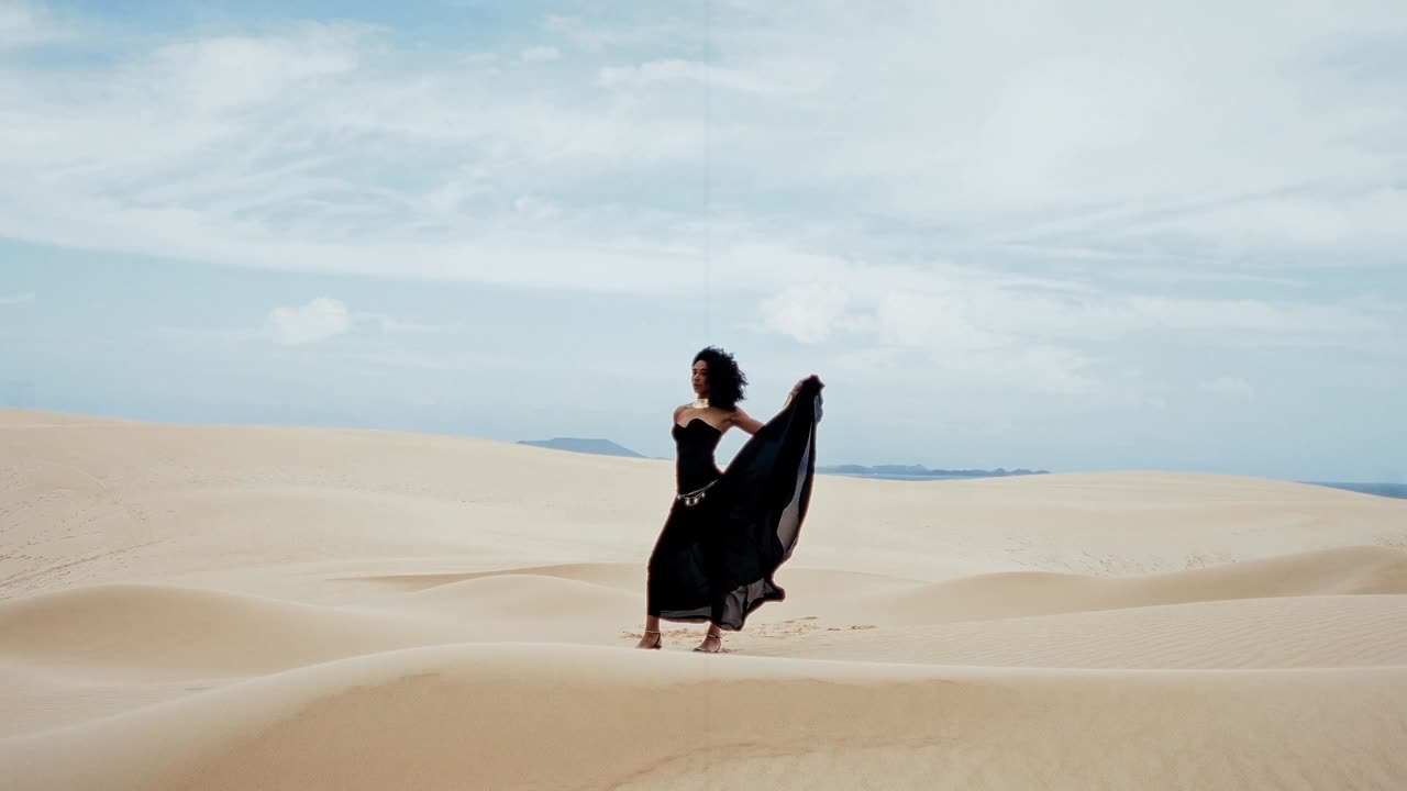 Woman in a black gown on a white sand dune