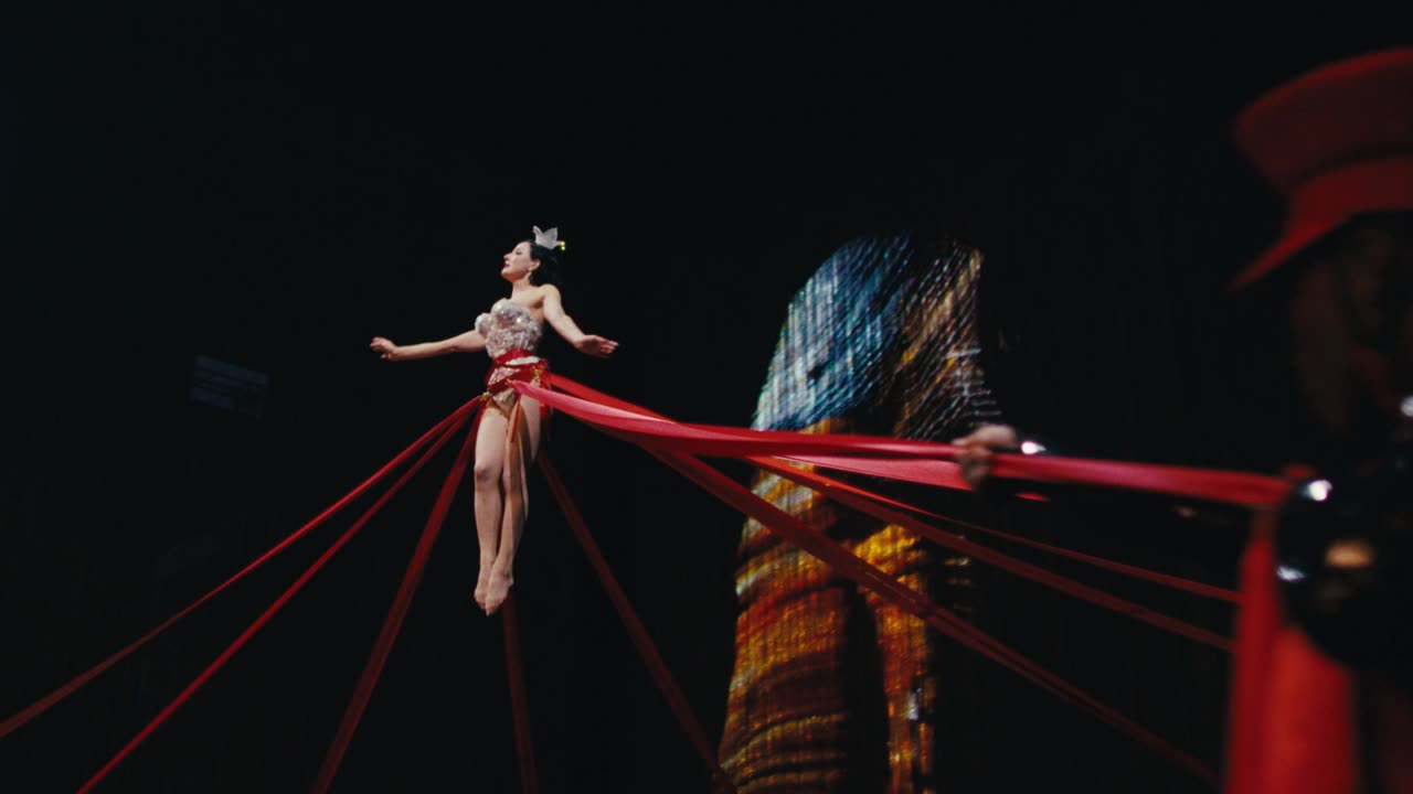 Performer bound in red ribbons on a cabaret stage